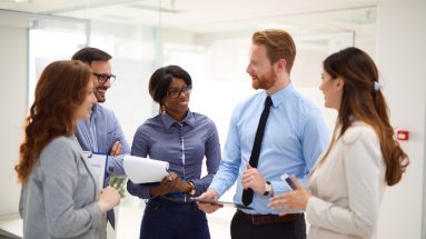 Group of successful business people is having casual staff meeting and discussing new business proposal and strategy using both digital tablet and printed media.